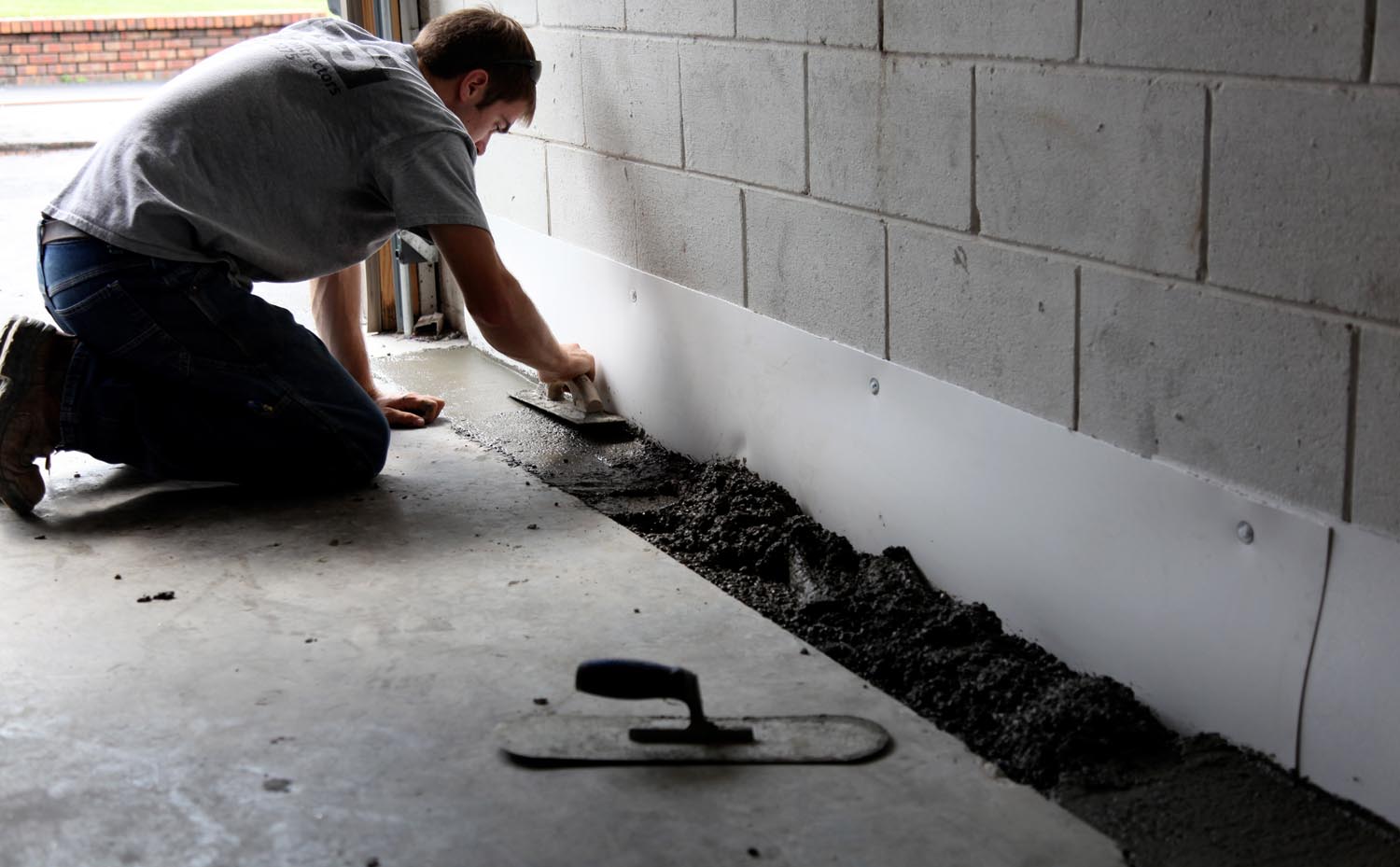 Harris Waterproofing Worker Sealing The Foundation Of A Home From The Interior, In Order To Waterproof The Basement